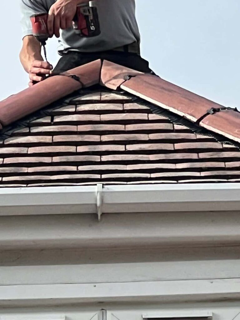 This is a photo of one of the operatives of Bilston Roofing Repairs installing new ridge tiles