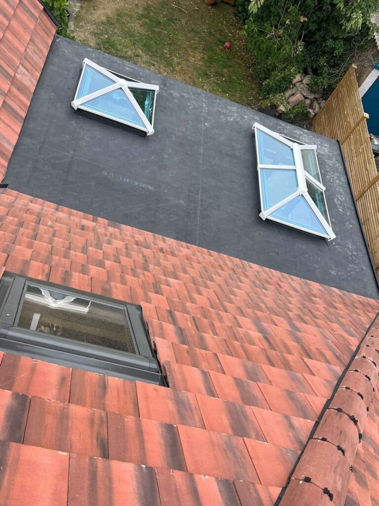This is a photo taken from the roof ridge looking down a tiled pitched roof on to a flat roof. Works carried out by Bilston Roofing Repairs